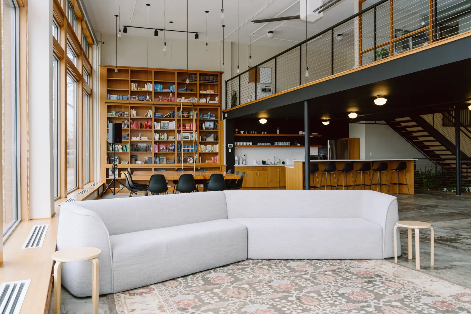 Open main floor with curved sofa, library wall and mezzanine